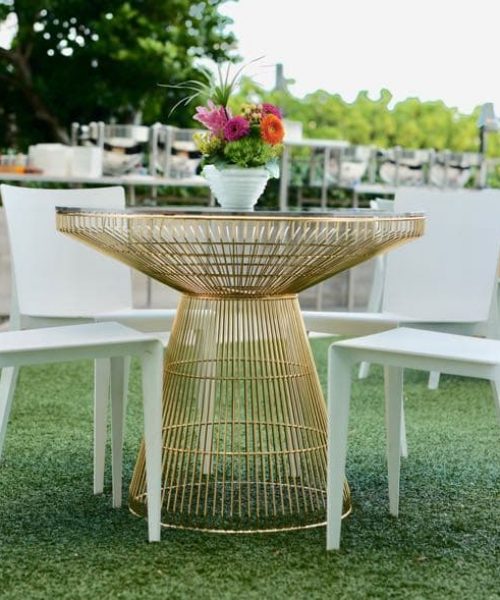 gold table with glass top and white chairs